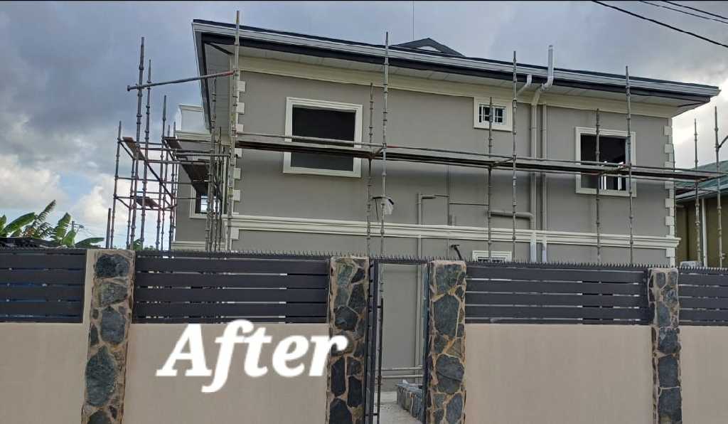 Residential building exterior marked after painting, with fence and scaffolding visible.