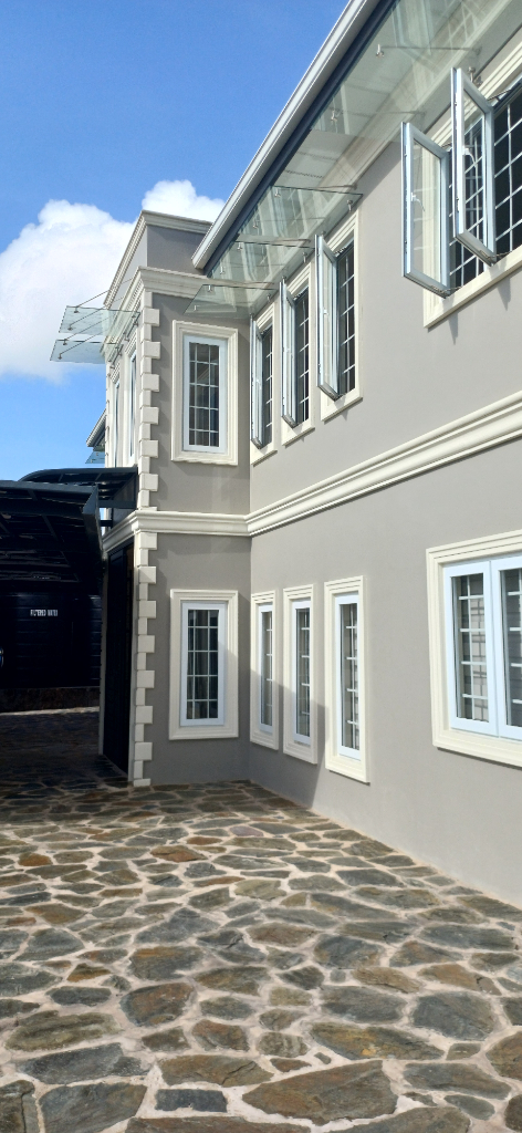 Completed grey exterior of a new residential building with white window mouldings and open windows.