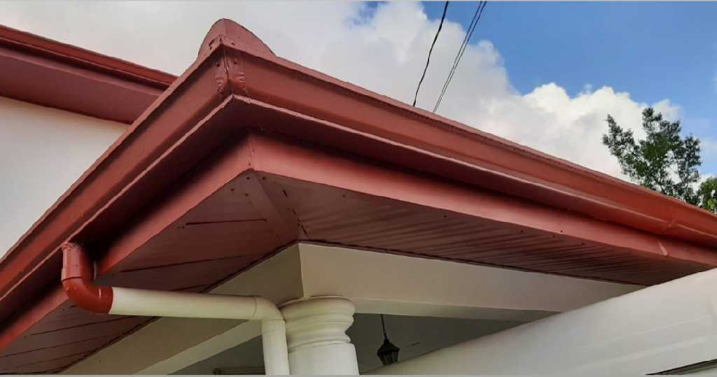 Close-up of a red-painted roof edge with light-coloured fascia and soffit.